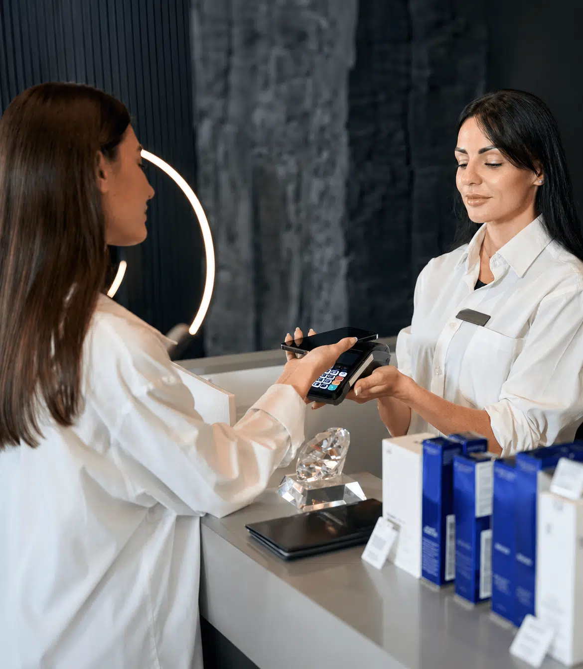 Customer paying by phone on a card terminal held by a retail associate at a checkout counter